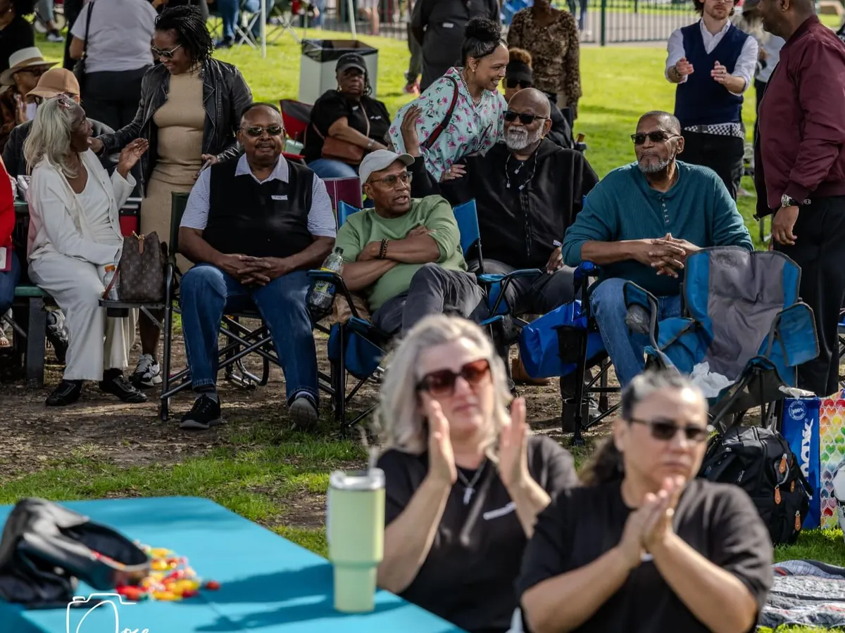 Neighbors in lawn chairs applauding on the grass