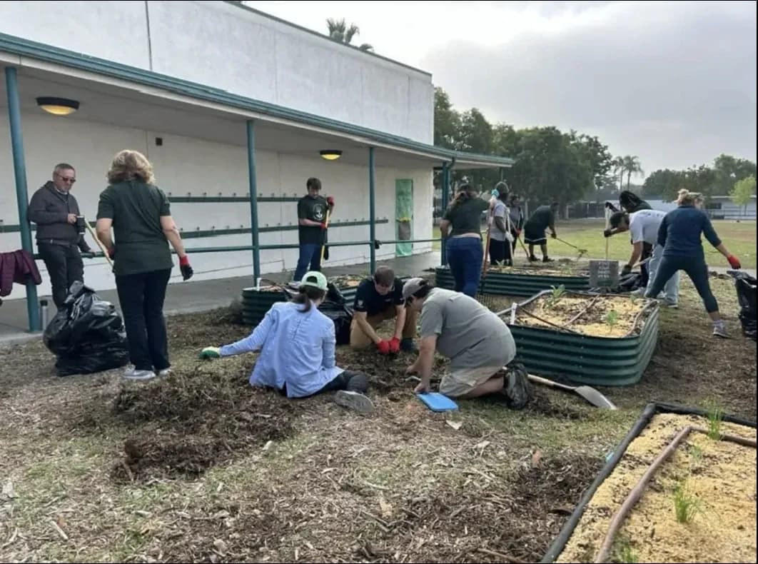 Volunteers weeding and planting raised garden beds on Make a Difference Day